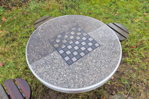 Das Bild zeigt einen von Witterungsbedingungen stark verunreinigten Steintisch auf einem Spielplatz in Teltow, der auf der Hälfte, wo er von WARRDAWAS gereinigt wurde richtig hellgrau bis fast weiß erscheint und auf der alten ungereinigten Seite dunkelgrau.