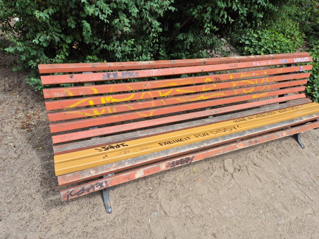 Das Foto zeigt eine mit Tags und Graffitis beschmierte Sitzbank an einem Spielplatz in Potsdam Babelsberg, vor der professionellen und umweltfreundlichen Reinigung durch WarDaWas.