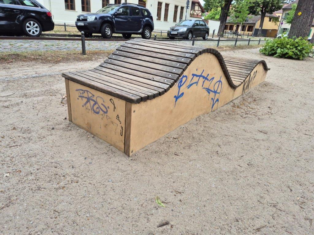 Das Bild zeigt ein mit Graffitis beschmiertes Kletterelement aus Holz auf einem Spielplatz in Potsdam Babelsberg, bevor es professionell und umweltfreundlich durch WarDaWas gereinigt wird.