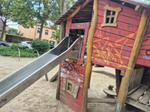 Das Foto zeigt ein mit Graffitis beschmiertes Kletterhaus aus Holz auf einem Spielplatz in Potsdam Babelsberg, bevor es professionell und umweltfreundlich von der Firma WarDaWas gereinigt wird.