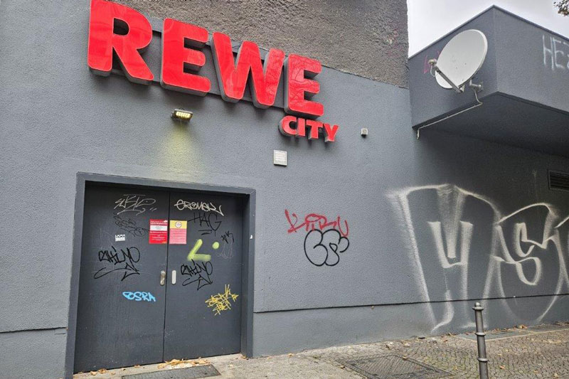 Hinteransicht der Rewe-City Filliale, in Berlin, bevor Wardawas sie gesäubert hat mit Tür und Putz großflächig von Grafitti verschmiert.