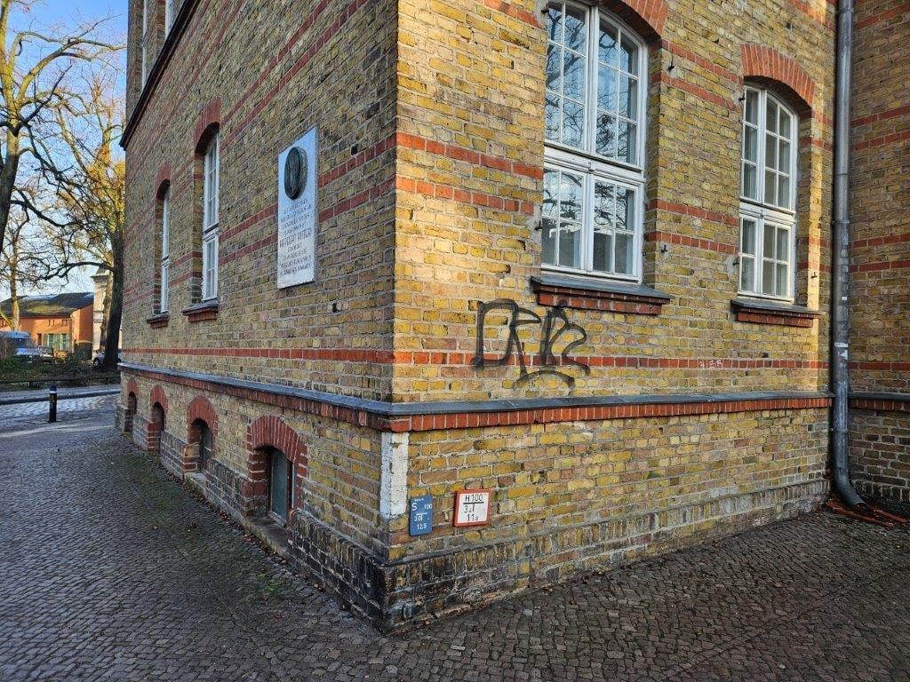 Eine mit Graffiti beschmierte Backsteinfassade, bevor von WarDaWas eine Spezialreinigung durchgeführt wurde.
