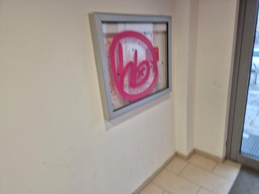 Eine gläserne Schautafel in der Sparkasse, die mit Graffiti beschmiert wurde, bevor WarDaWas eine Graffiti-Entfernung durchgeführt hat.