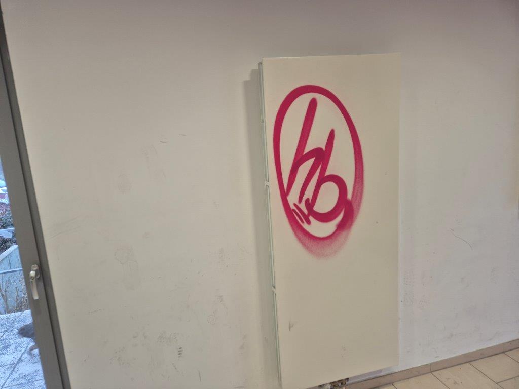 Das Bild zeigt einen weißen Heizkörper, der mit rotem Graffiti beschmiert wurde, vor der Graffiti-Entfernung durch WarDaWas.