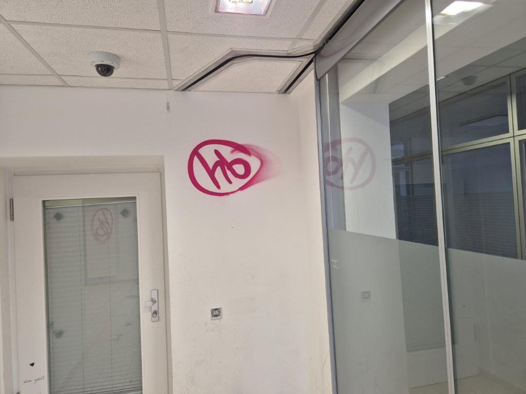 Eine weiße Wand im Innenraum einer Sparkasse, die mit einem roten Graffiti beschmiert wurde, vor der Graffiti-Entfernung durch WarDaWas