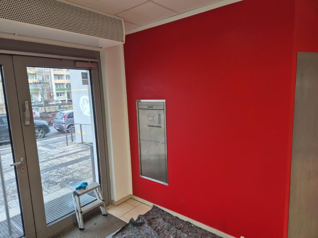Eine rote Wand im Innenraum einer Sparkasse, die vom Graffiti befreit wurde.