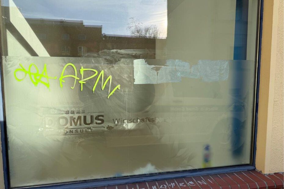Das Bild zeigt ein mit Klebefolie beklebtes und mit Graffiti beschmiertes Fenster eines Bürogebäudes vor der Entfernung durch WarDaWas