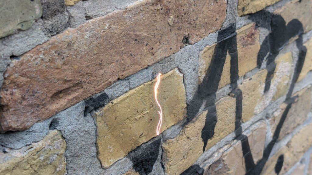 Nahaufnahme der Laserreinigung bei der Entfernung schwarzer Farbe von historischem Klinker