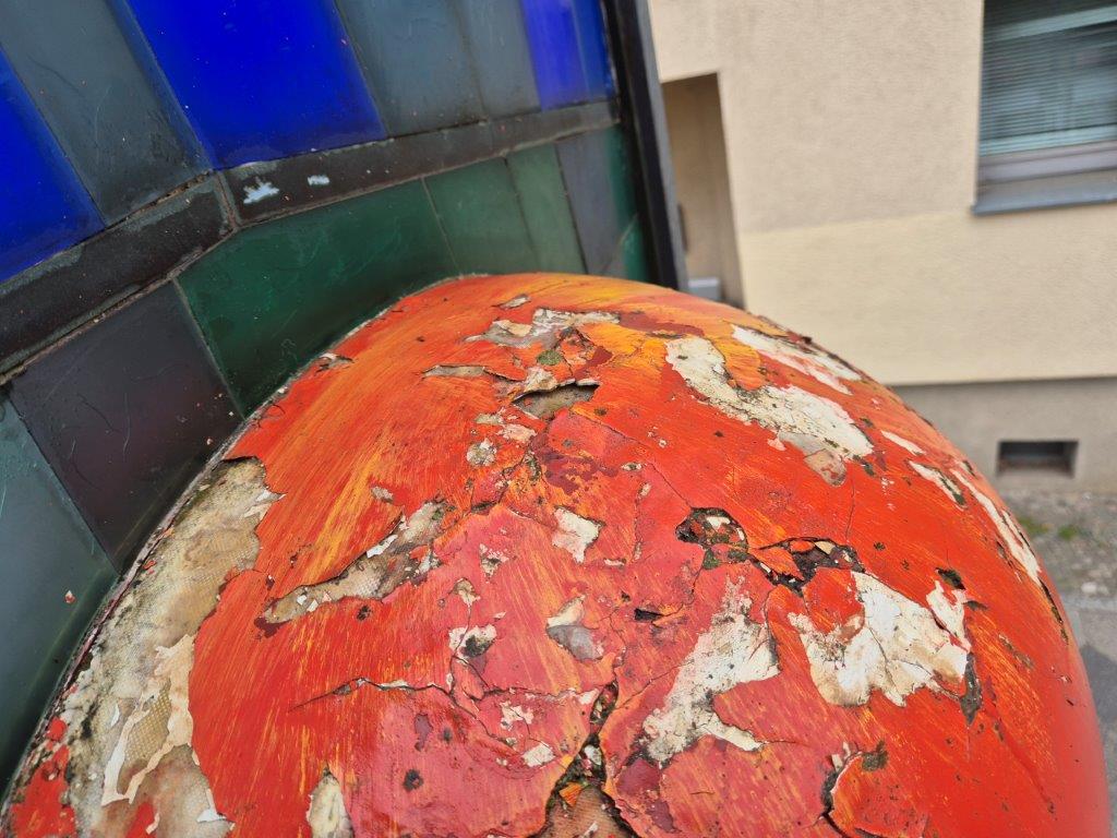 Verwittertes Kunstobjekt Apfel in Babelsberg mit abgeplatzter Farbe vor der Reinigung